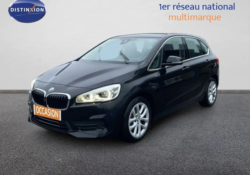 BMW Série 2 Active Tourer noir saphir métal vue 3/4 avant droit avec phares allumés sur fond neutre.