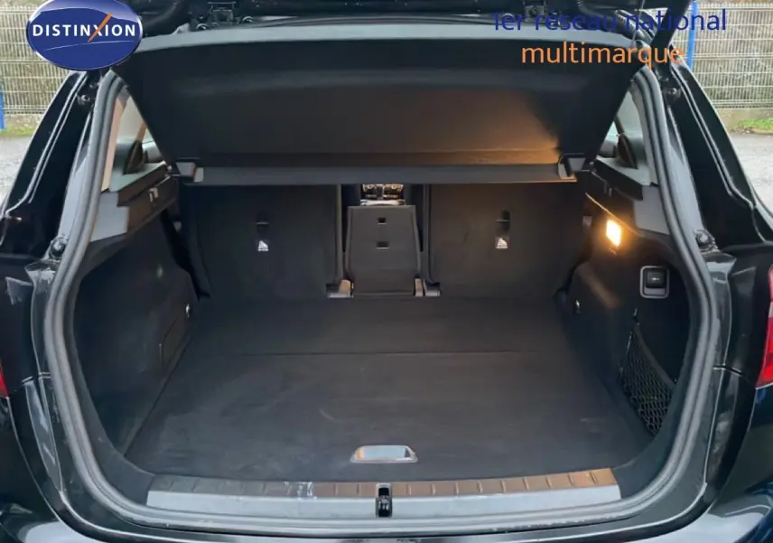Coffre ouvert vu de l'arrière d'une BMW Série 2 Active Tourer noir saphir métal, intérieur spacieux et éclairage latéral allumé.
