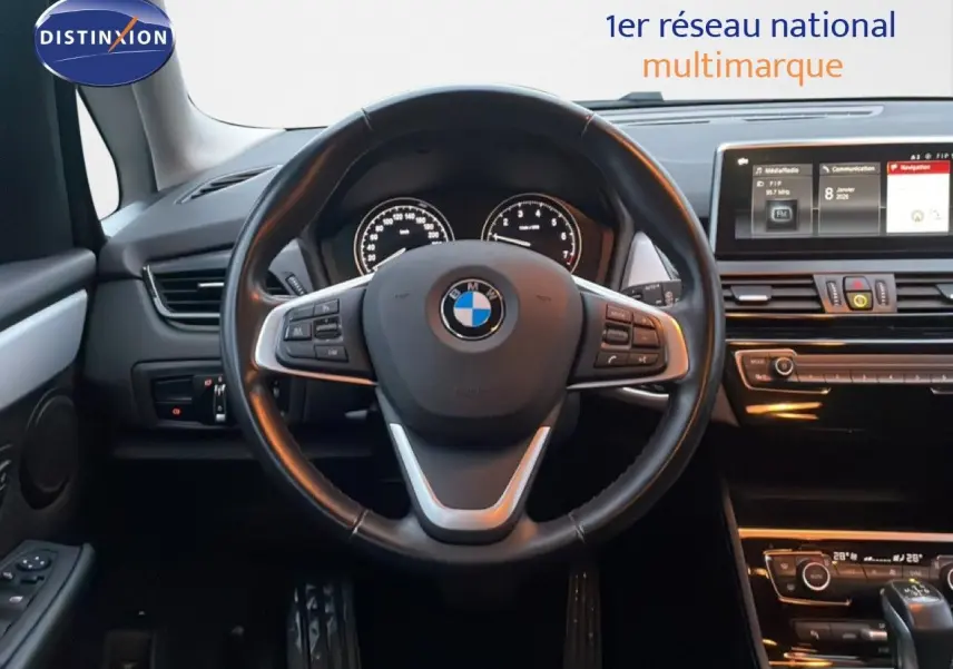 Vue intérieure centrée sur le volant cuir noir d'une BMW Série 2 Active Tourer 225XE avec tableau de bord et écran multimédia.