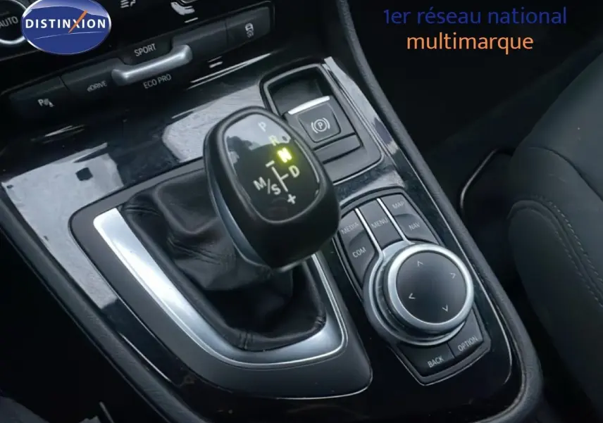 Gros plan sur la console centrale de la BMW Série 2 Active Tourer noire, avec levier de vitesse et commandes multimédia visibles.