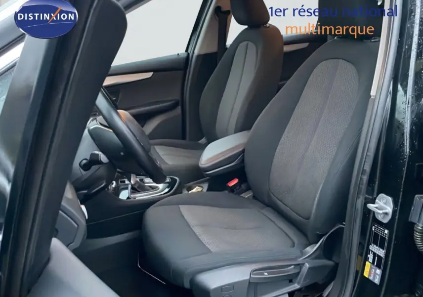 Vue intérieure côté conducteur d'une BMW Série 2 Active Tourer noire, montrant les sièges avant en tissu et cuir.