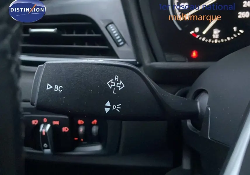 Gros plan sur la commande de clignotants à gauche du volant dans l’habitacle noir d’une BMW Série 2 Active Tourer 225XE.