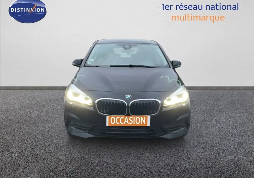 Vue frontale d'une BMW Série 2 Active Tourer noire avec phares allumés sur fond neutre.
