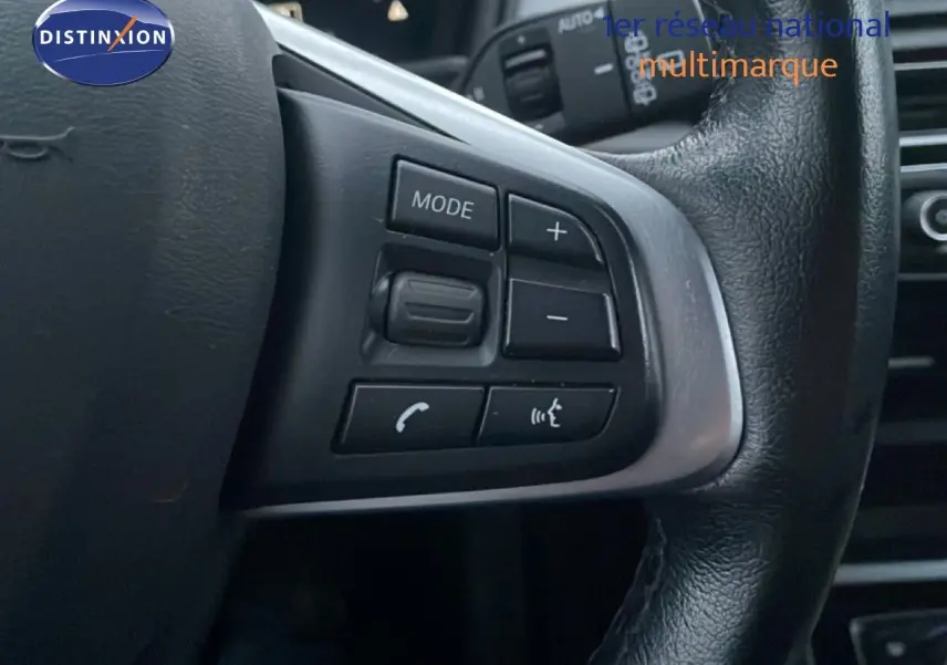 Gros plan sur les commandes au volant en cuir noir d'une BMW Série 2 Active Tourer 225XE 2021, finition Business Design.