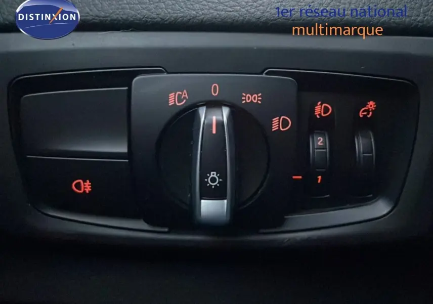Gros plan sur le panneau de commande des phares avec réglages lumineux, intérieur noir du BMW Série 2 Active Tourer.