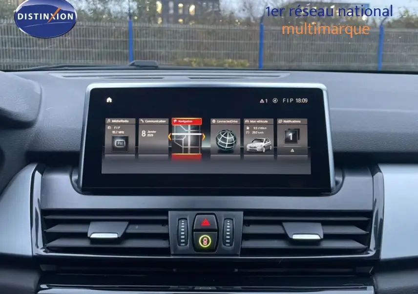 Vue intérieure du tableau de bord de la BMW Série 2 Active Tourer 225XE, écran central affichant la navigation et les options connectées.