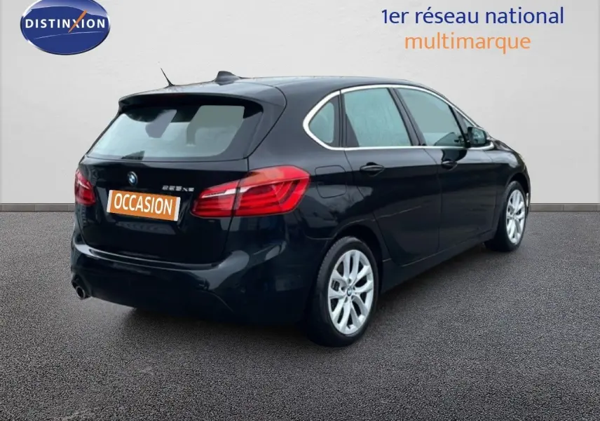 BMW Série 2 Active Tourer noir saphir métal vue 3/4 arrière droit sur sol gris, avec feux arrière allumés.