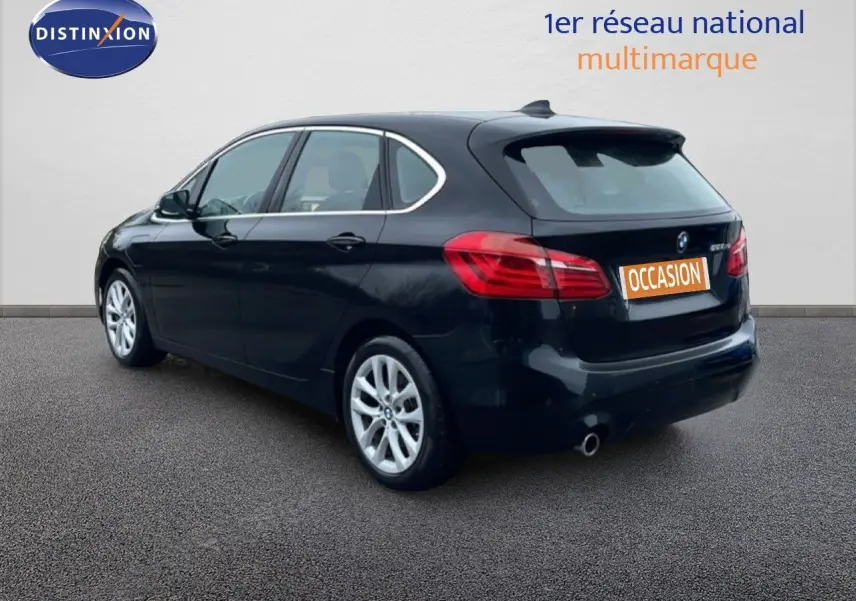 BMW Série 2 Active Tourer noir saphir métal en 3/4 arrière droit, avec jantes argentées et feux arrière visibles.