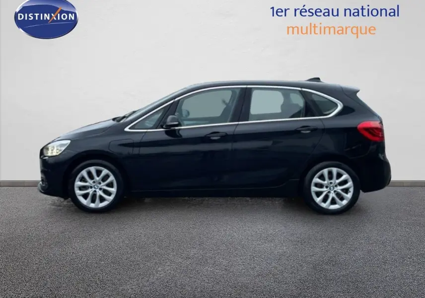 Profil latéral droit d'une BMW Série 2 Active Tourer noire Saphir Métal, avec jantes alliage et lignes fluides.