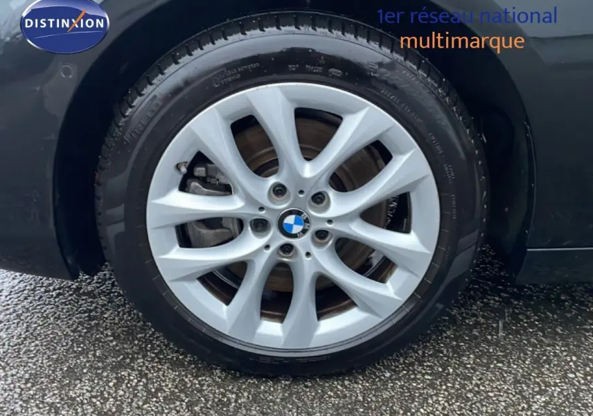 Gros plan sur la roue avant droite d’une BMW Série 2 Active Tourer noire avec jante alliage argentée à dix branches.
