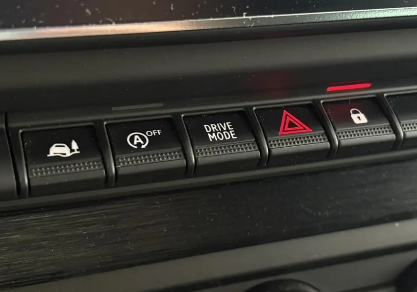 Gros plan sur les boutons de commande du tableau de bord du Nissan Primastar gris, avec mode conduite et alerte.