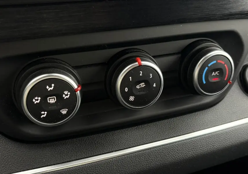 Gros plan sur les commandes de climatisation du Nissan Primastar gris, avec réglages de ventilation, vitesse et température.