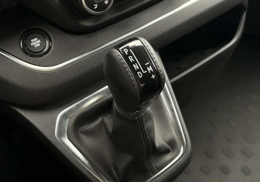 Gros plan sur le levier de vitesses automatique noir du Nissan Primastar 2025, entouré de garniture argentée et bouton start engine stop.