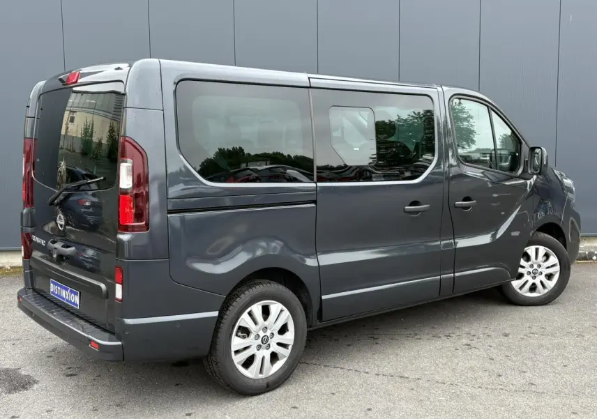 Vue 3/4 arrière droite du Nissan Primastar gris comète avec hayon vitré et jantes alliage 17 pouces.