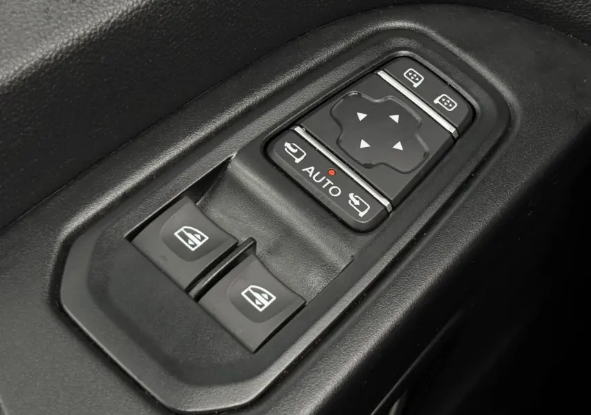 Gros plan sur les commandes de lève-vitres et réglages des rétroviseurs du Nissan Primastar gris Comète, côté conducteur.