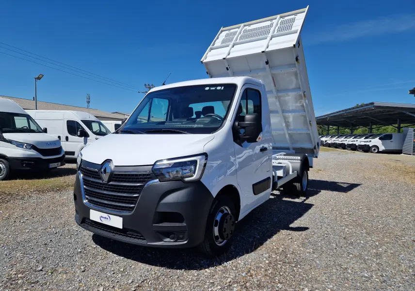 Vue 3/4 avant gauche d'un Renault Master blanc avec benne relevée et roues jumelées sur un terrain extérieur.