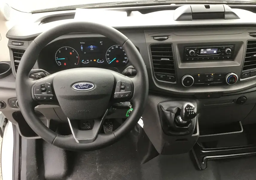 Vue intérieure centrée sur le volant et le tableau de bord noir du Ford Transit Chassis Cabine blanc avec boîte manuelle.