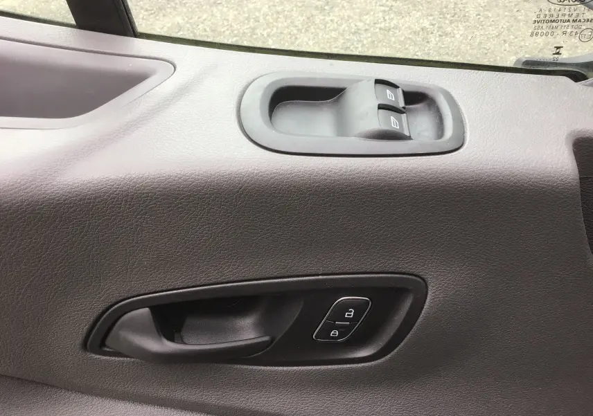 Poignée de porte intérieure côté gauche du Ford Transit Chassis Cabine blanc avec commandes de verrouillage et lève-vitres.