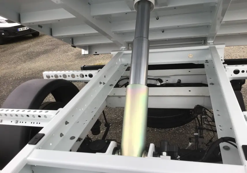 Vue rapprochée sous la benne blanche du Ford Transit Chassis Cabine, montrant le vérin hydraulique et le châssis acier.