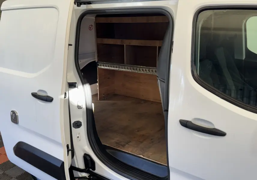 Vue latérale droite d’un Citroën Berlingo blanc 2020 avec porte coulissante ouverte montrant l’espace de chargement en bois.