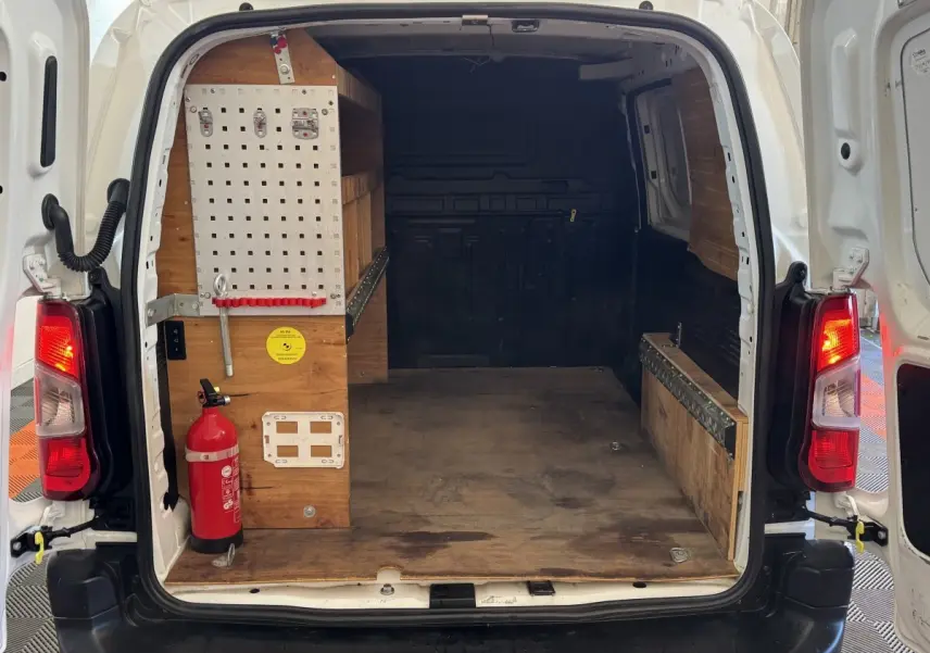 Vue arrière ouverte du Citroën Berlingo blanc 2020, montrant l’espace de chargement avec aménagements en bois et extincteur.