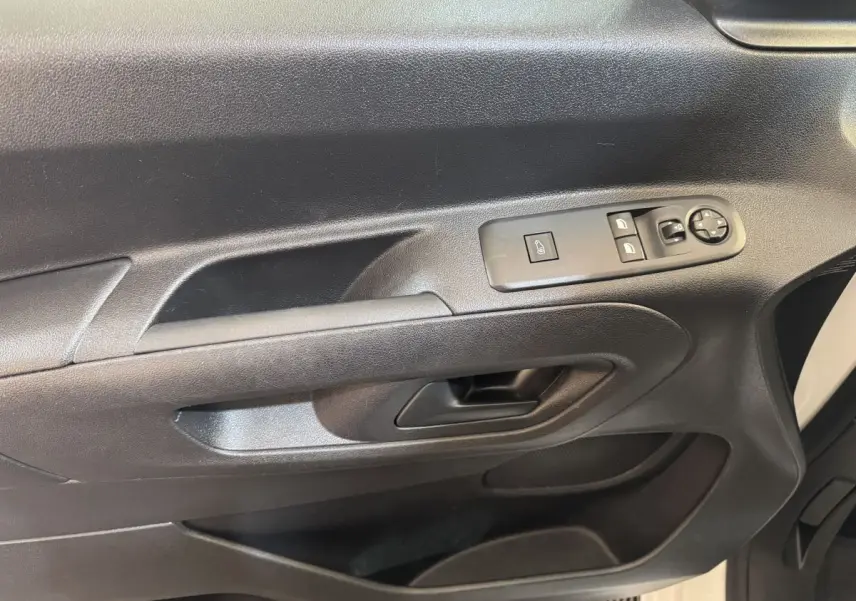 Gros plan sur la porte intérieure côté conducteur du Citroën Berlingo blanc, avec commandes électriques et poignée noire.