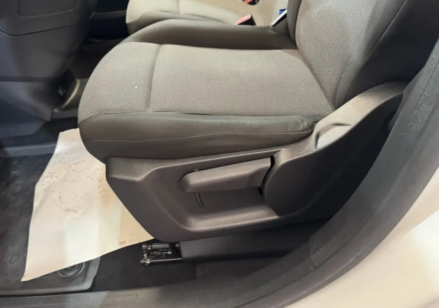 Gros plan sur le siège avant droit gris du Citroën Berlingo blanc, montrant la manette de réglage latérale.