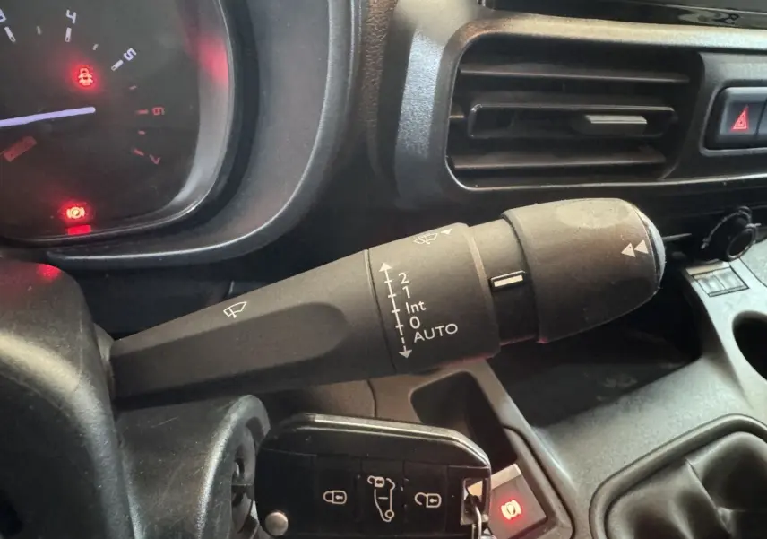 Gros plan sur la commande d’essuie-glace à gauche du volant dans l’habitacle du Citroën Berlingo blanc 2020.