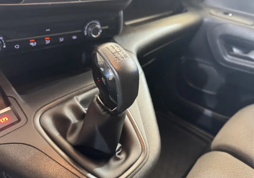 Gros plan sur le levier de vitesses manuel noir dans l’habitacle du Citroën Berlingo blanc, côté passager.