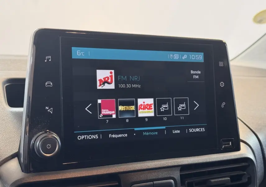 Écran tactile central du tableau de bord du Citroën Berlingo blanc, affichant les stations radio FM.