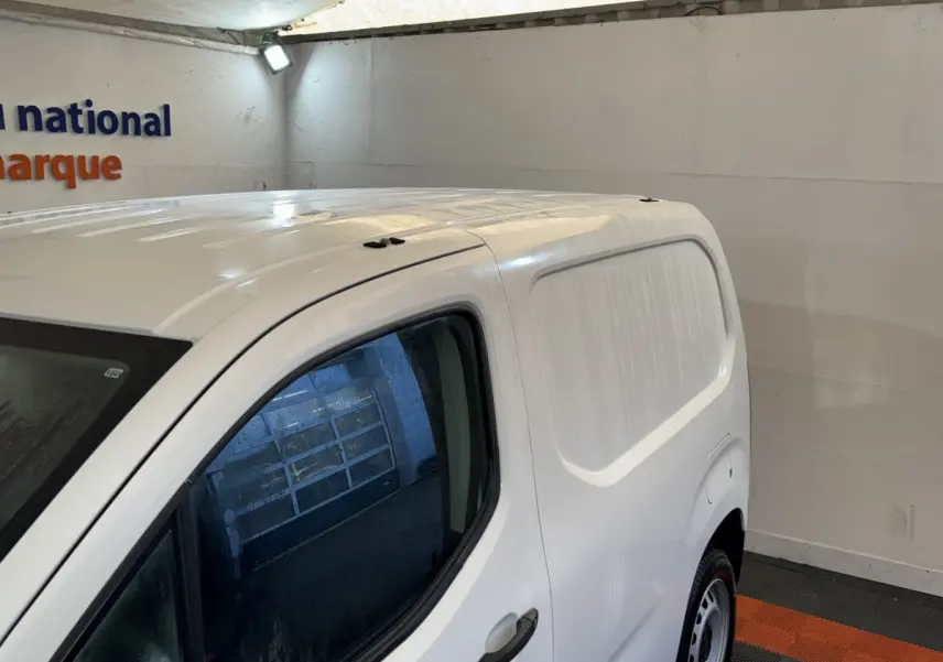 Vue 3/4 avant droit du Citroën Berlingo blanc utilitaire avec porte latérale pleine, stationné en intérieur.