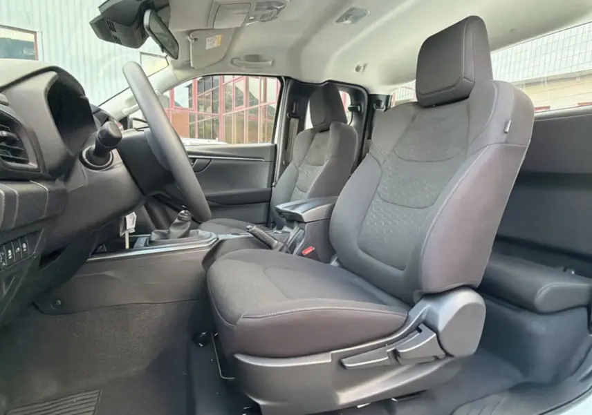 Intérieur du pick-up Isuzu D-MAX 2026, vue côté gauche sur les sièges avant en tissu gris avec accoudoir central.