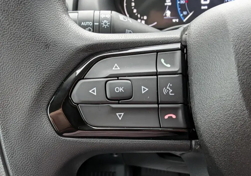 Gros plan sur les commandes multifonctions du volant côté gauche du Citroën Jumper blanc 2025.