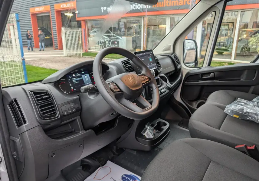 Intérieur avant droit du Citroën Jumper blanc 2025 montrant tableau de bord numérique et sièges tissu noir.