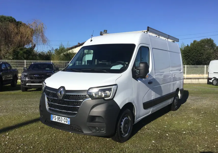 Renault Master blanc en 3/4 avant droit avec galerie de toit et pare-chocs noir visible sur parking extérieur.