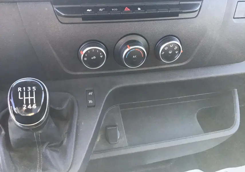 Vue intérieure de la partie arrière ouverte d'un Renault Master blanc 2020 avec étagères métalliques et parois boisées.