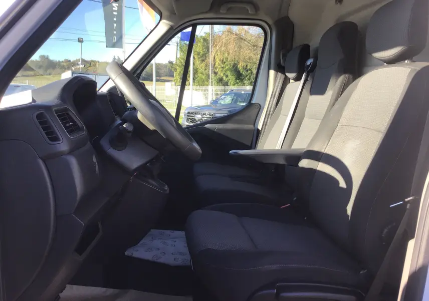 Vue intérieure côté conducteur du Renault Master 2020, sièges tissu noir et gris avec accoudoir central.