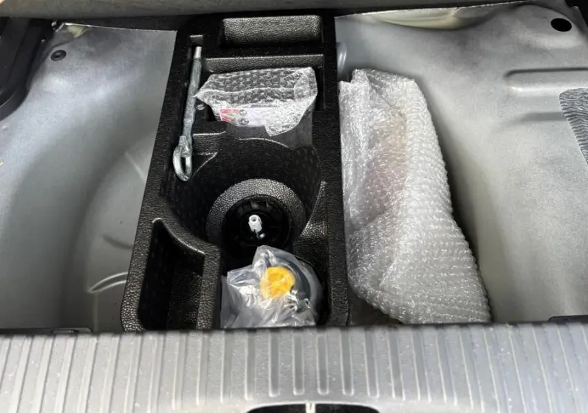 Coffre ouvert du Citroën C3 Aircross 2021, vue plongeante sur rangement noir avec outils emballés et tapis gris.