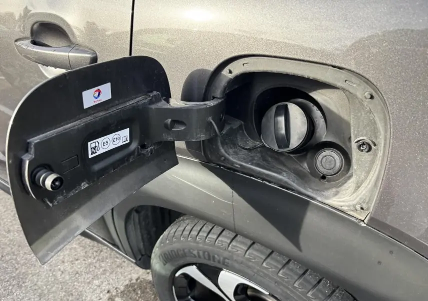 Gros plan sur la trappe à carburant ouverte côté gauche d’un Citroën C3 Aircross gris platinium avec jante alliage 17 pouces.