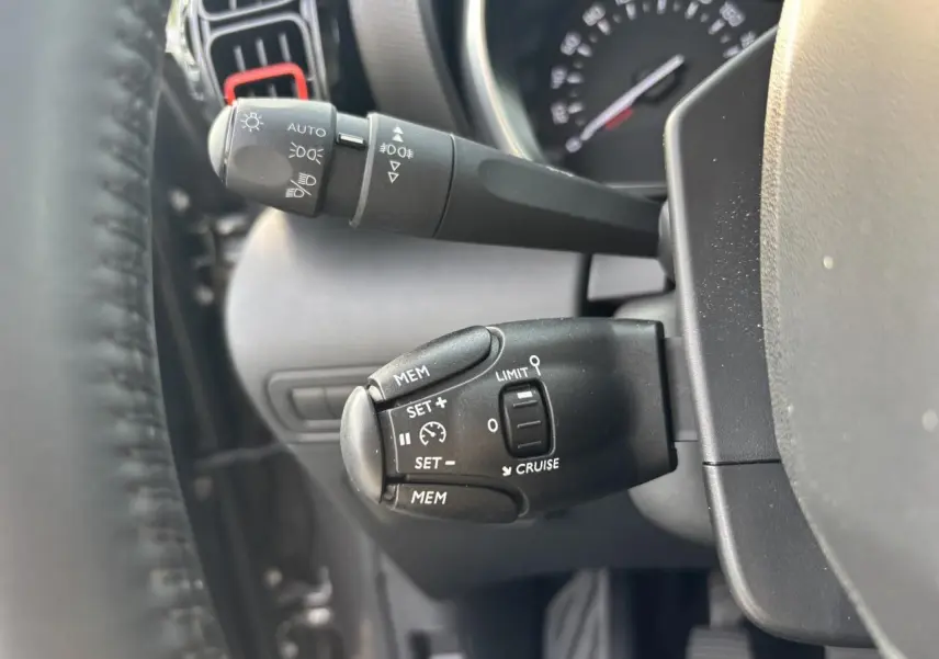 Gros plan sur les commandes au volant noir du Citroën C3 Aircross 2021, côté gauche du tableau de bord gris.