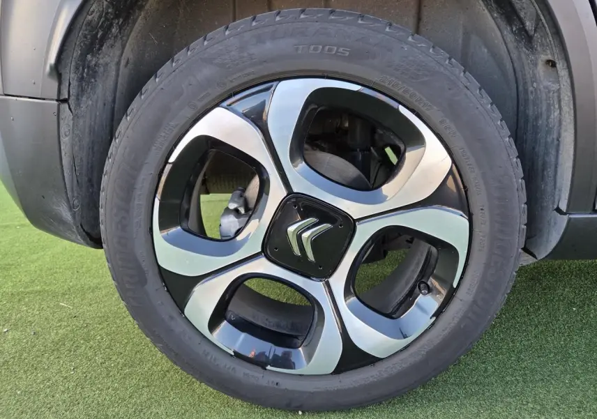 Gros plan sur la jante alliage diamantée 17'' noire et argentée d'un Citroën C3 Aircross gris platinium.