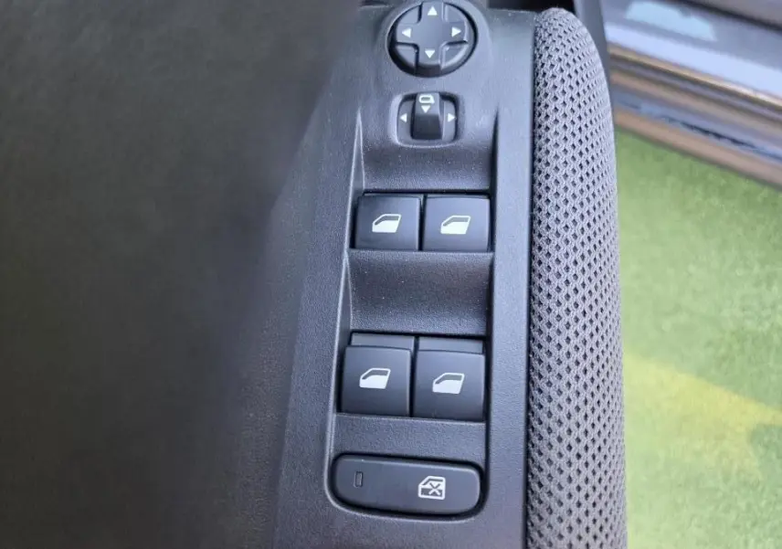 Gros plan sur les commandes de lève-vitres et réglages des rétroviseurs côté conducteur du Citroën C3 Aircross gris.