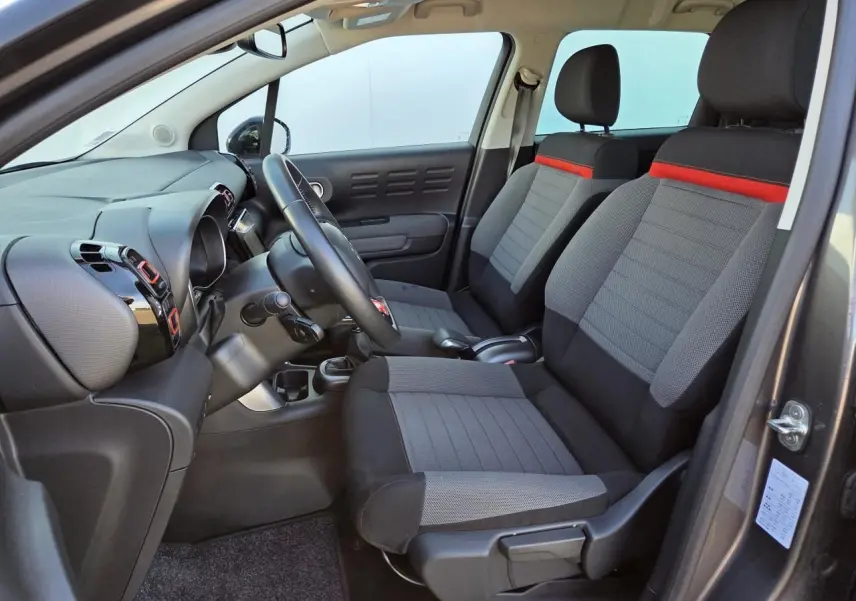 Intérieur avant droit de Citroën C3 Aircross gris platinium, sièges tissu gris avec bande rouge et tableau de bord noir brillant.
