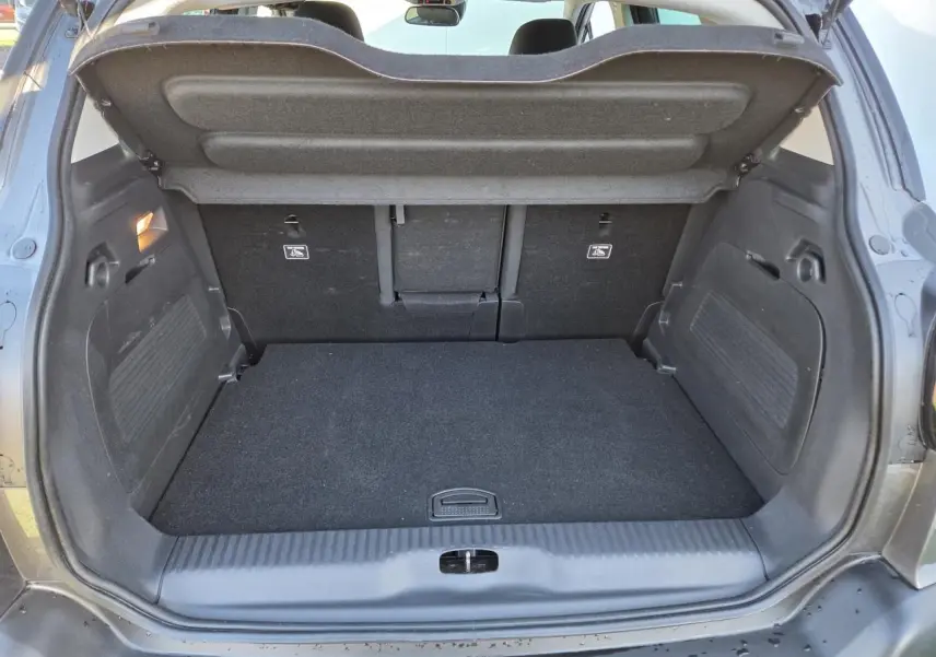 Coffre ouvert vu de l'arrière d'un Citroën C3 Aircross gris platinium avec banquette arrière rabattue partiellement.
