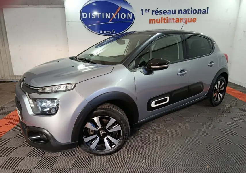 Citroën C3 gris foncé vue 3/4 avant droit avec protections latérales noires et jantes bicolores.
