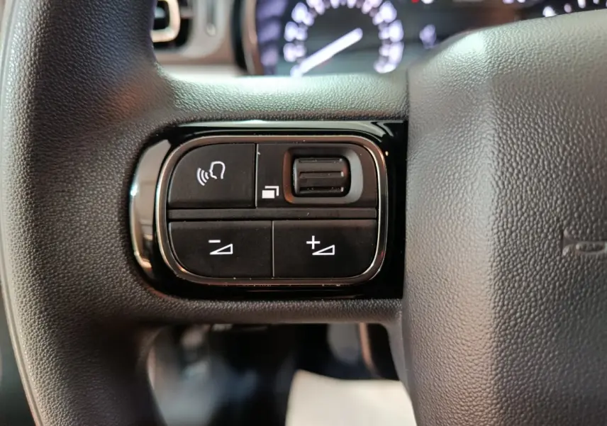 Gros plan sur les commandes de volume et téléphone sur le volant noir de la Citroën C3 2024.