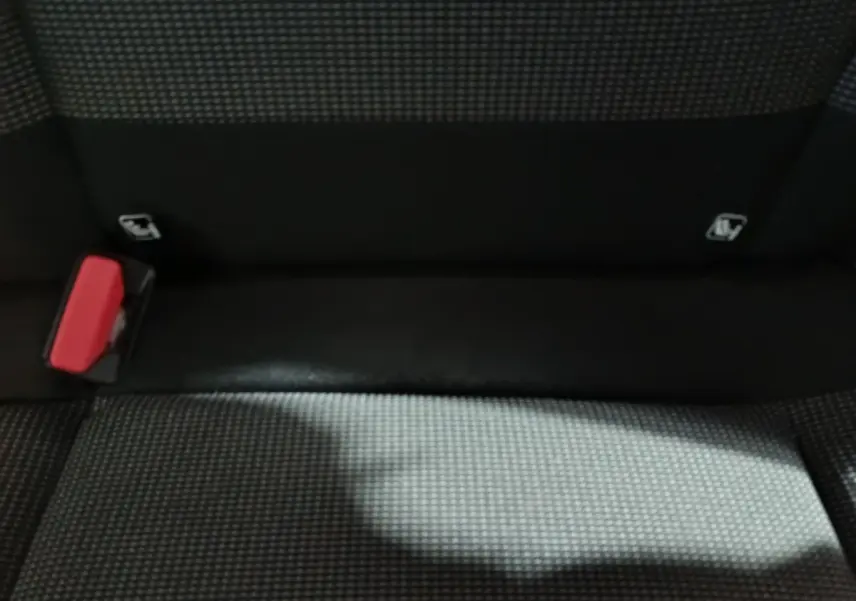 Gros plan sur la banquette arrière gris foncé de la Citroën C3 avec boucle de ceinture rouge visible à gauche.