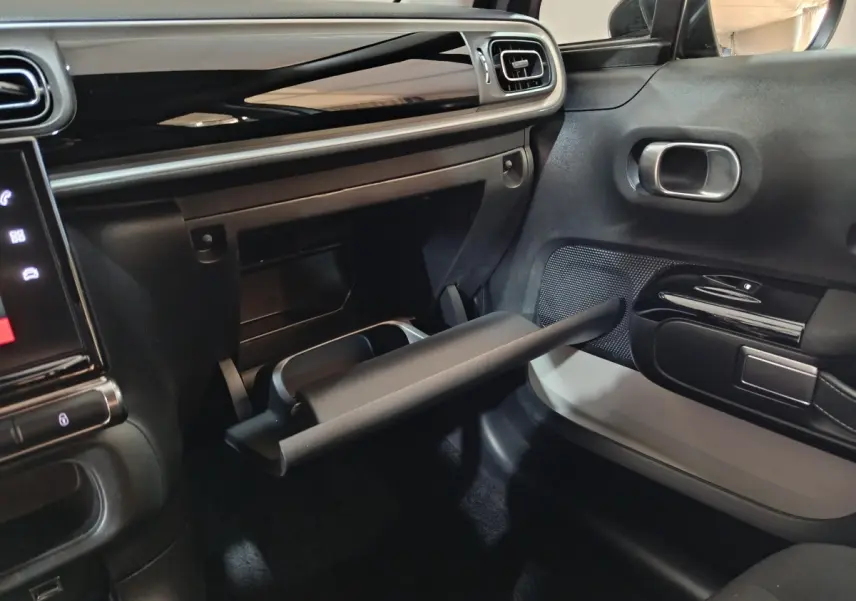 Intérieur de la Citroën C3 PureTech 83 BVM MAX 2024, vue côté passager sur la boîte à gants ouverte et tableau de bord noir.