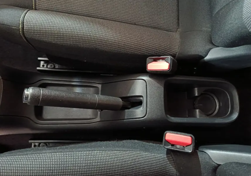 Vue plongeante sur la console centrale noire avec frein à main manuel et ceintures rouges de la Citroën C3 gris foncé 2024.