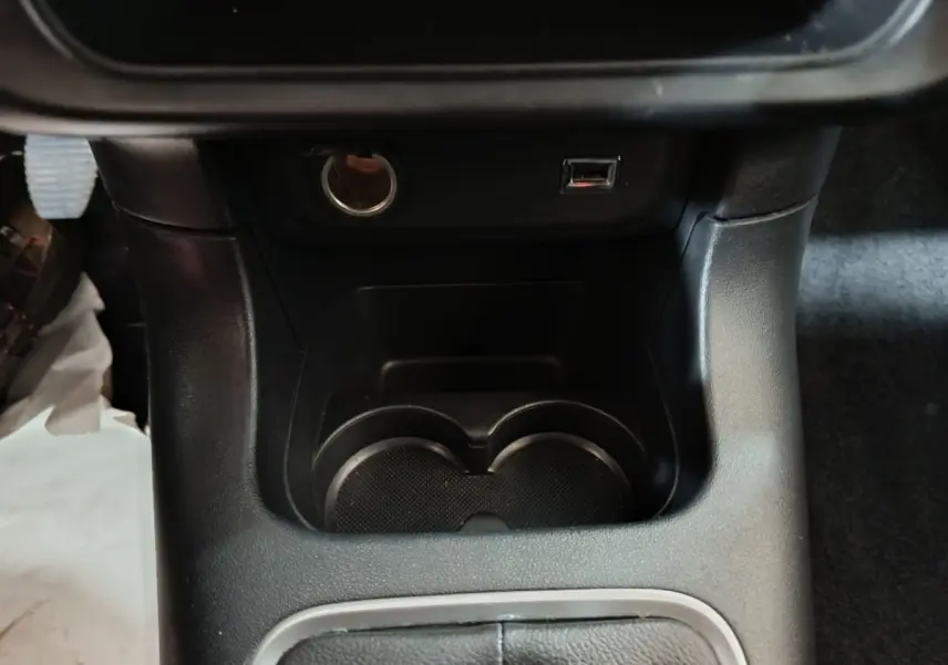 Gros plan sur la console centrale noire de la Citroën C3 2024 avec prises USB et allume-cigare visibles.